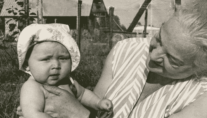 Black and white photo of a grandmother holding a baby in a hat.