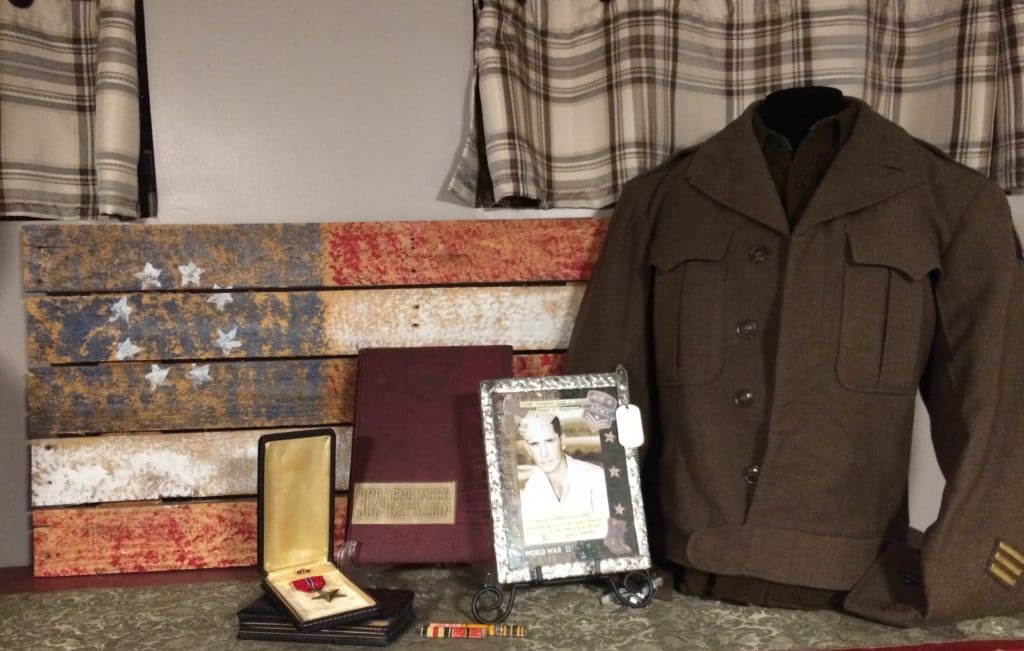 An example of military heirlooms displayed at home including a flag, uniform and framed photo.