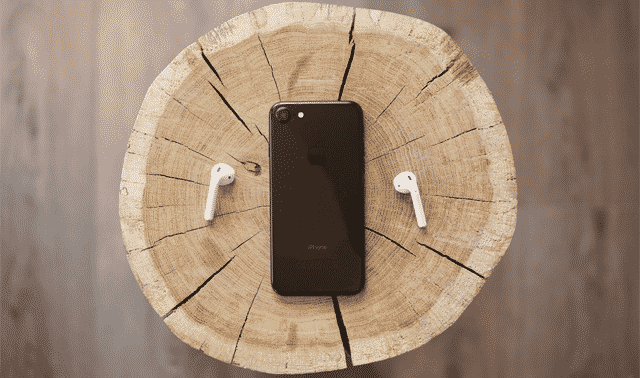 mobile phone on a tree stump with wireless headphones