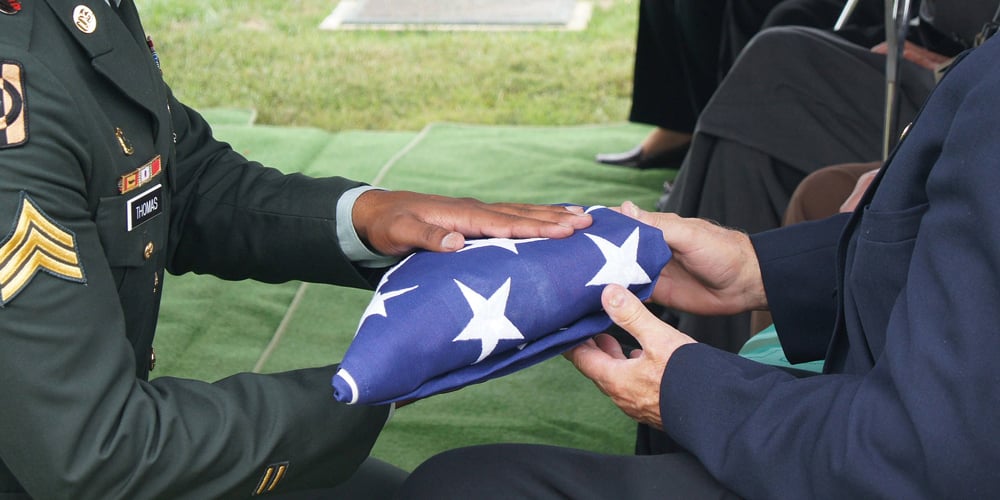 Men in uniform holding a folded American flag.