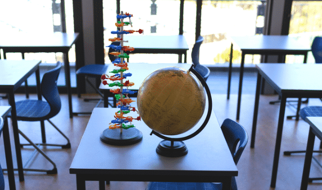 Globe and DNA model sitting on a desk in a sunny classroom.