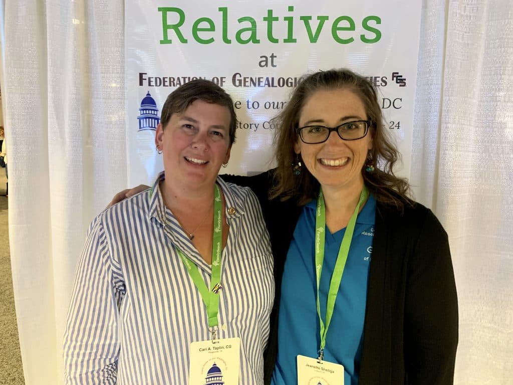 Two women at a genealogy conference smiling at the camera.