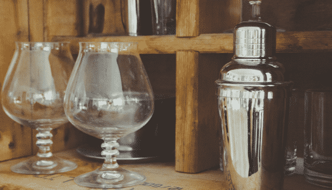 Vintage cocktail glasses on a wooden shelf.