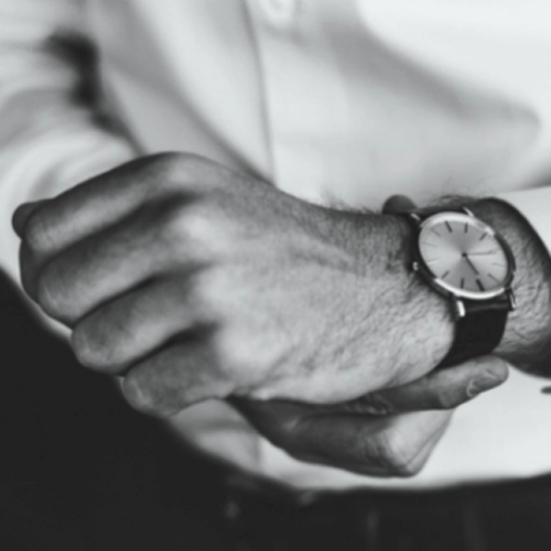Man in a white shirt putting on a watch.